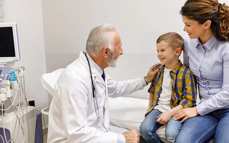 Ein Junge ist mit seiner Mutter beim Kinderarzt, der mit ihnen über Lebensmittelallergien spricht.