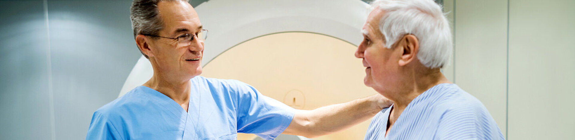 Ein Radiologe spricht mit einem älteren Patienten. Die Protonentherapie hilft bei zahlreichen Krebserkrankungen.