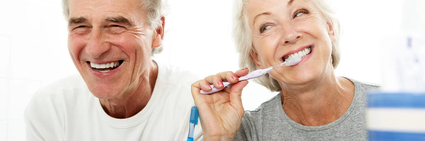 Ein älteres Paar putzt gemeinsam im Bad Zähne. 