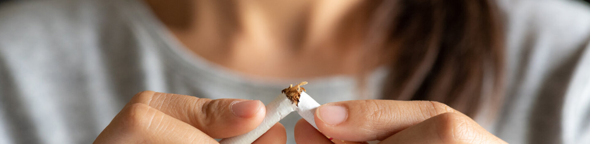 Eine Frau zerbricht eine Zigarette. Die AOK unterstützt alle Versicherten dabei, Nichtraucher zu werden.
