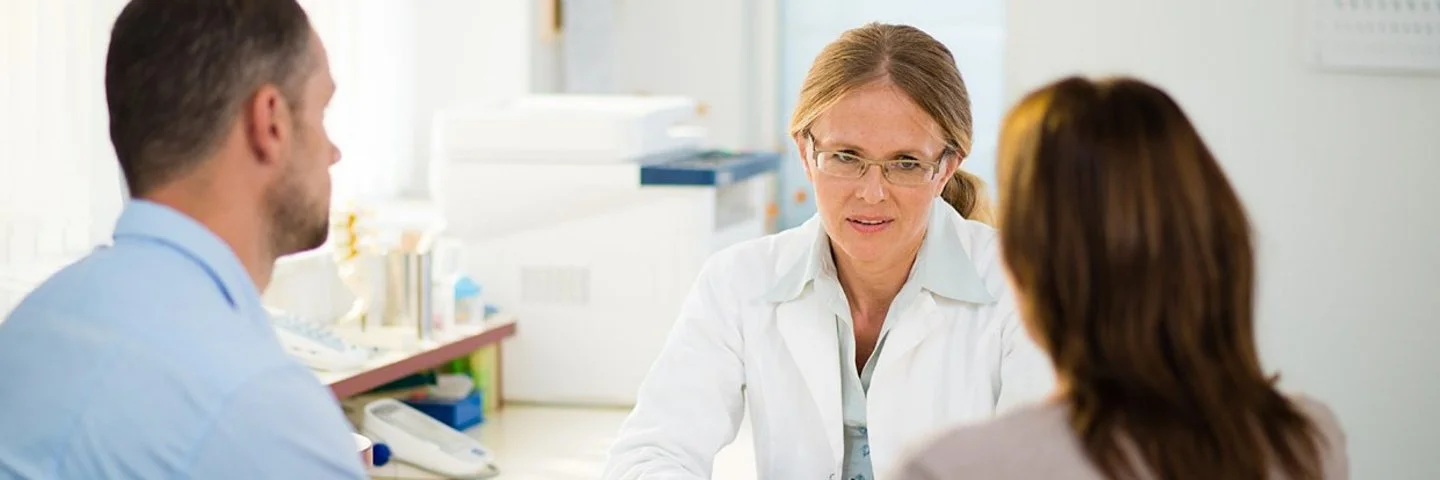 Ein Paar mittleren Alters in einer Beratungssituation mit dem Hausarzt, es besteht Verdacht einer Krebserkrankung