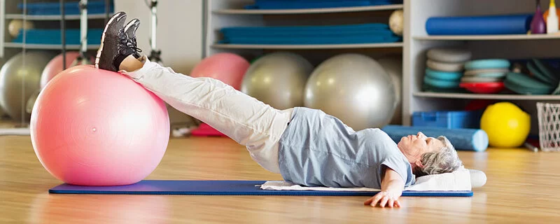 Frau, die an Inkontinenz im Alter leidet, macht Beckenbodentraining mit einem Gymnastikball.