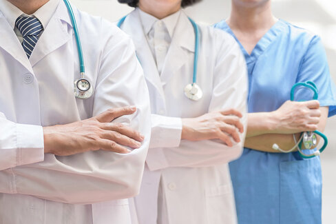 Ein Arzt, eine Ärztin und eine Krankenschwester stehen nebeneinander. Die Experten von AOK-Clarimedis decken viele Fachgebiete ab.