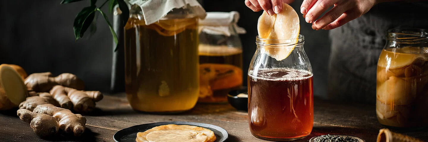 Eine Person entnimmt aus einem großen Glasgefäß die Pilzkultur zum Fermentieren
