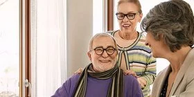 Ein altes Paar spricht mit einer Pflegeberaterin. Die Pflegeberaterin erklärt in einem Beratungsgespräch, wie sich die Pflege organisieren lässt.