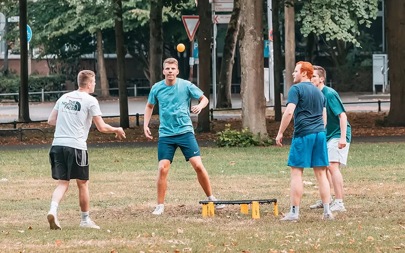 Vier Männer spielen Roundnet auf einer Grünfläche.