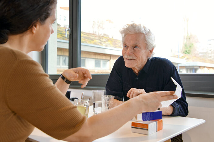Eine Frau zeigt einem älteren Mann die Packungsbeilage eines Arzneimittels. Die AOK informiert über Medikamente und über Zuzahlungen.