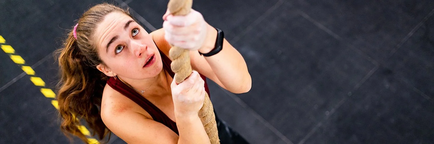 Eine Frau klettert an einem Seil hoch.