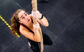 Eine Frau klettert an einem Seil hoch.