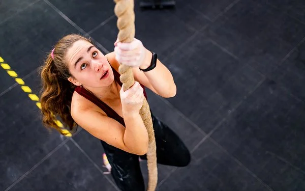 Eine Frau klettert an einem Seil hoch.