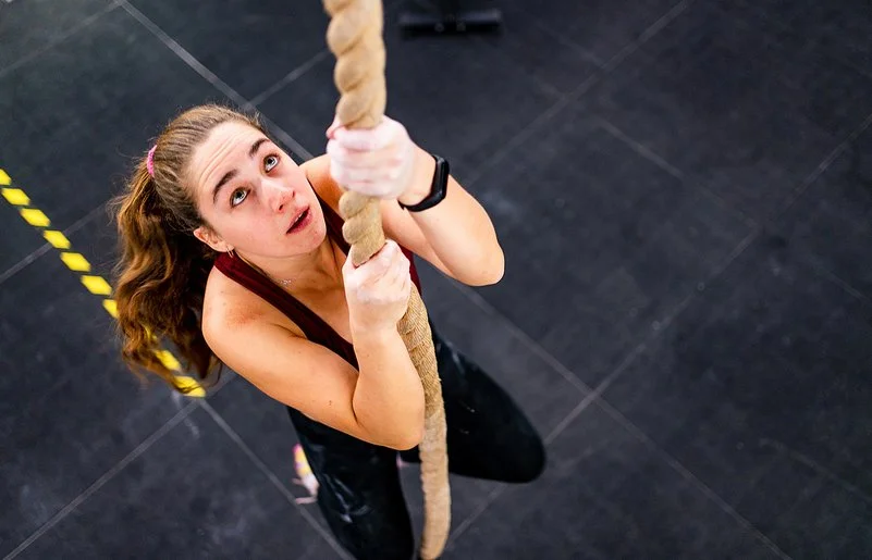 Eine Frau klettert an einem Seil hoch.