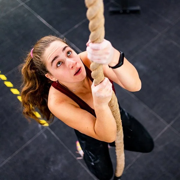 Eine Frau klettert an einem Seil hoch.