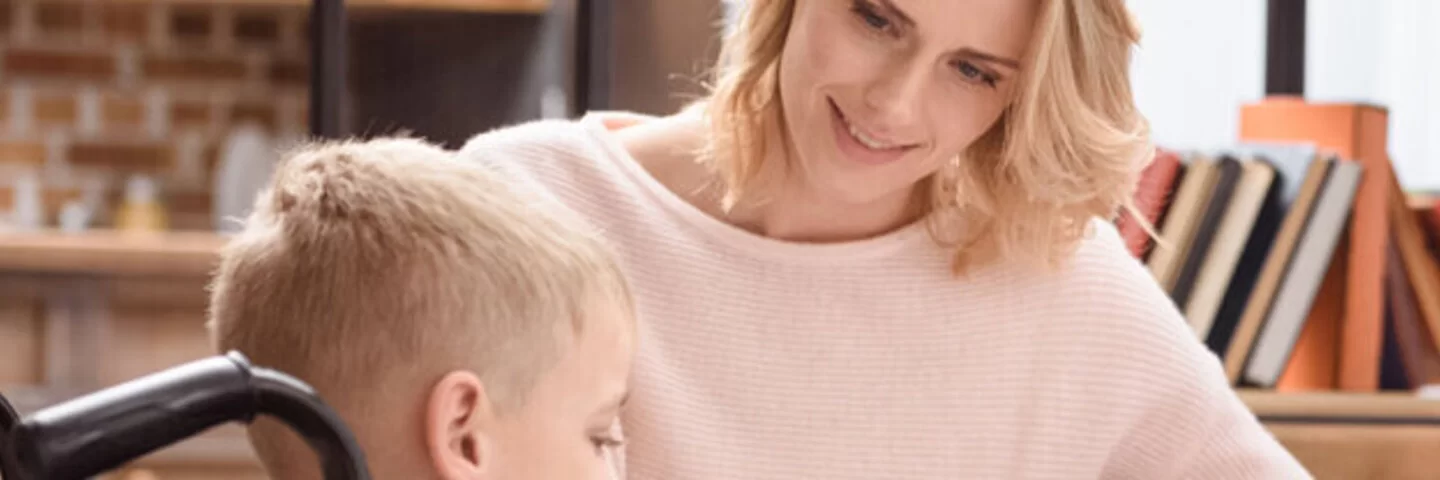 Das Bild zeigt eine Mutter, die sich um ihren pflegebedürftigen Sohn kümmert.