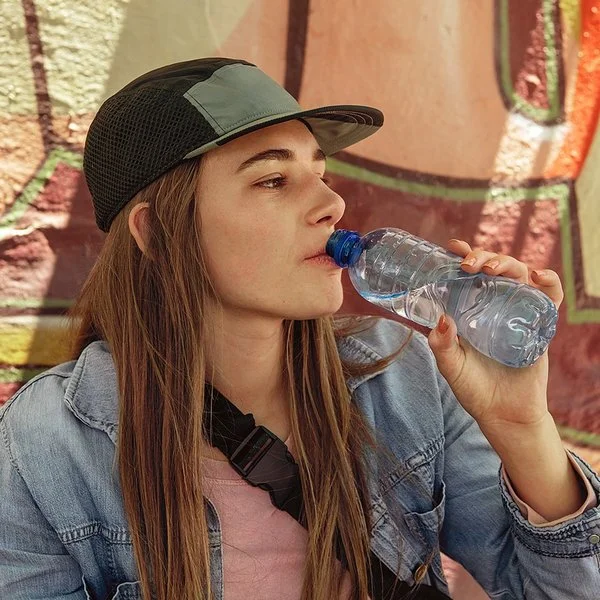 Frau trinkt Wasser aus einer Plastikflasche, dabei kann Mikroplastik in den Körper gelangen.