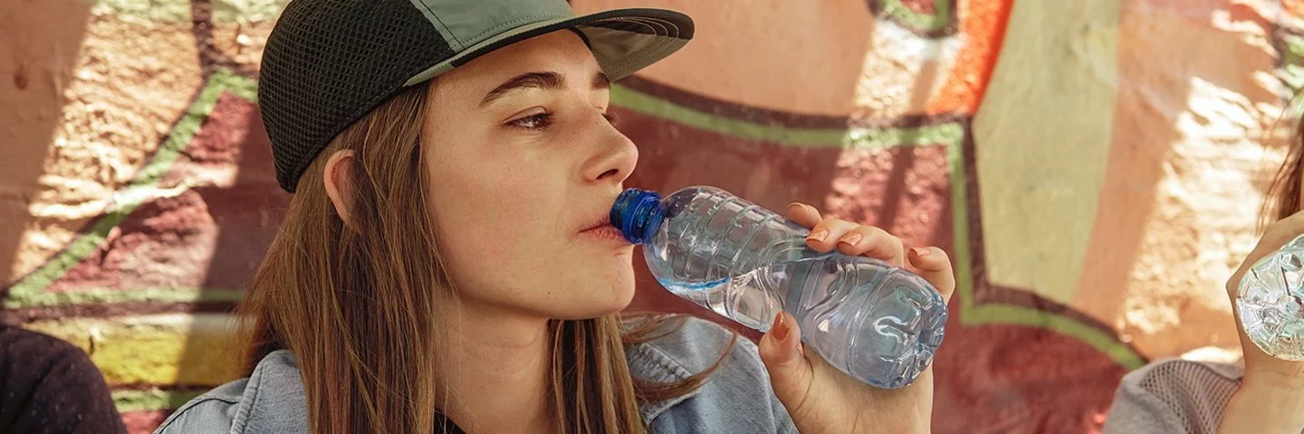 Frau trinkt Wasser aus einer Plastikflasche, dabei kann Mikroplastik in den Körper gelangen.
