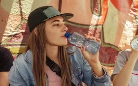 Frau trinkt Wasser aus einer Plastikflasche, dabei kann Mikroplastik in den Körper gelangen.