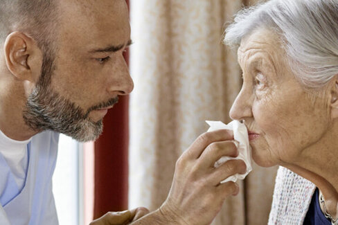Eine Pflegekraft hilft einer älteren Frau beim Essen.