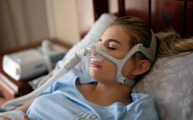 Eine Frau trägt eine CPAP-Maske beim Schlafen.