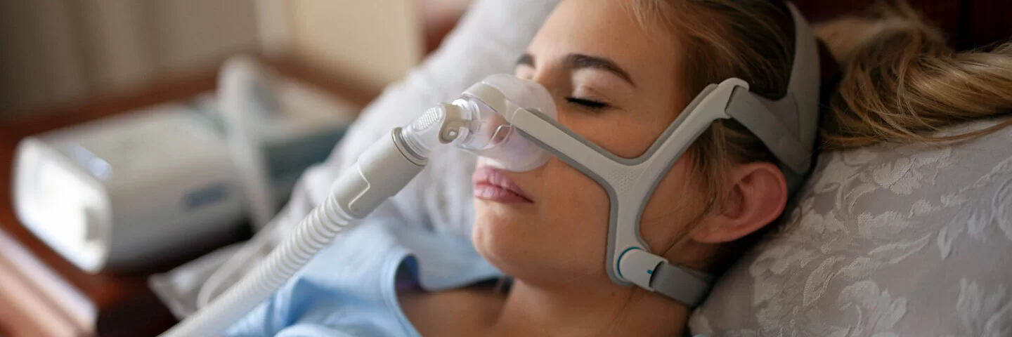 Eine Frau trägt eine CPAP-Maske beim Schlafen.
