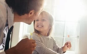 Kind hat die Zähne geputzt und zeigt sie seinem Vater