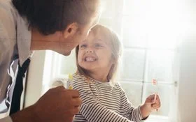 Kind hat die Zähne geputzt und zeigt sie seinem Vater