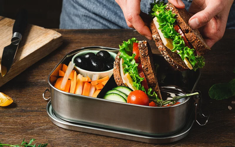 Eine Frau will sich gesund ernähren und bereitet eine Lunchbox vor.