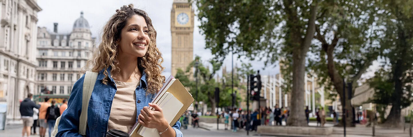 Eine junge Frau geht in London im Freien spazieren und trinkt Kaffee.