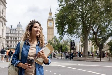 Eine junge Frau geht in London im Freien spazieren und trinkt Kaffee.