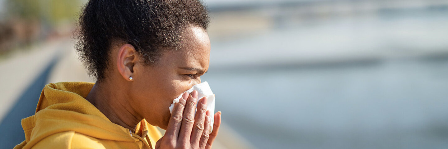 Eine erkältete Frau putzt sich nach dem Sport die Nase
