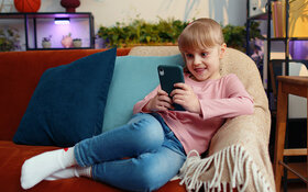 Ein Mädchen spielt mit einem Smartphone und ist dabei Werbung ausgesetzt.
