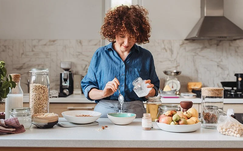 Eine Frau fügt Kokosöl zu ihrem Müsli hinzu.