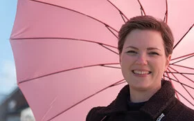 Frau mit Schirm an einem sonnigen Tag.