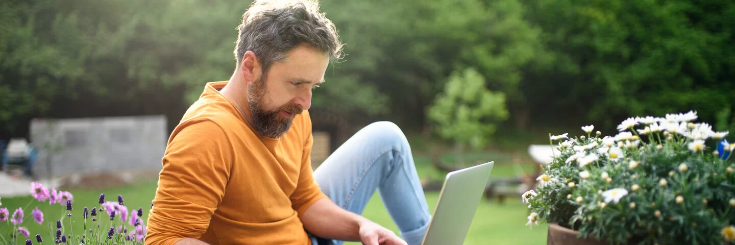 Reifer Mann mit Laptop arbeiten im Freien im Garten, Home-Office-Konzept. – Stockfoto