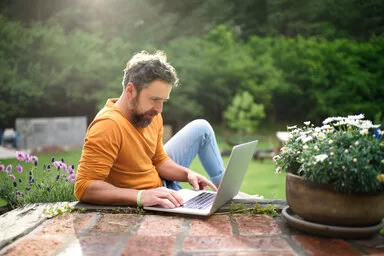 Reifer Mann mit Laptop arbeiten im Freien im Garten, Home-Office-Konzept. – Stockfoto