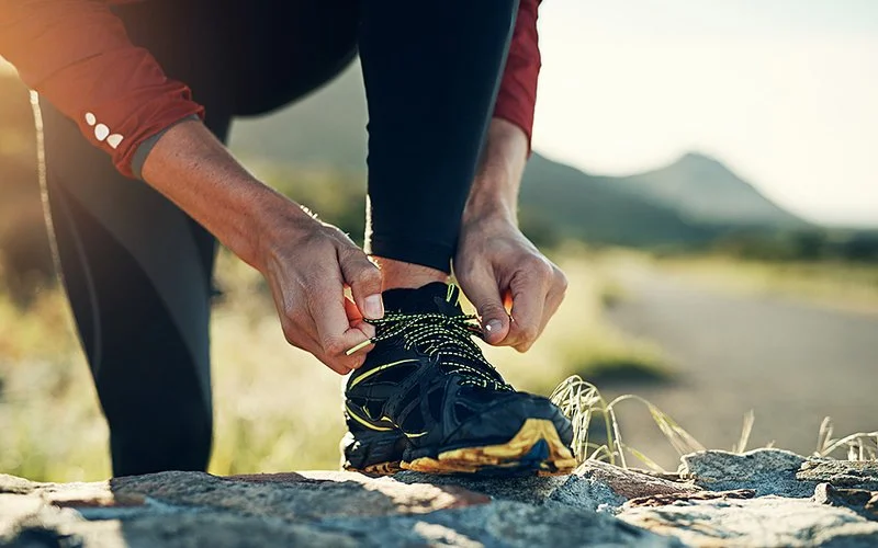Ein Mann bindet sich die Schnürsenkel seiner Laufschuhe zu.