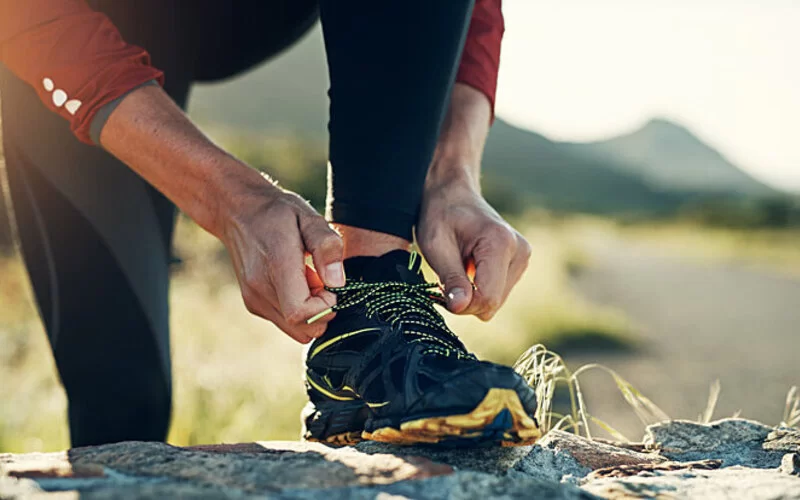 Ein Mann bindet sich die Schnürsenkel seiner Laufschuhe zu.