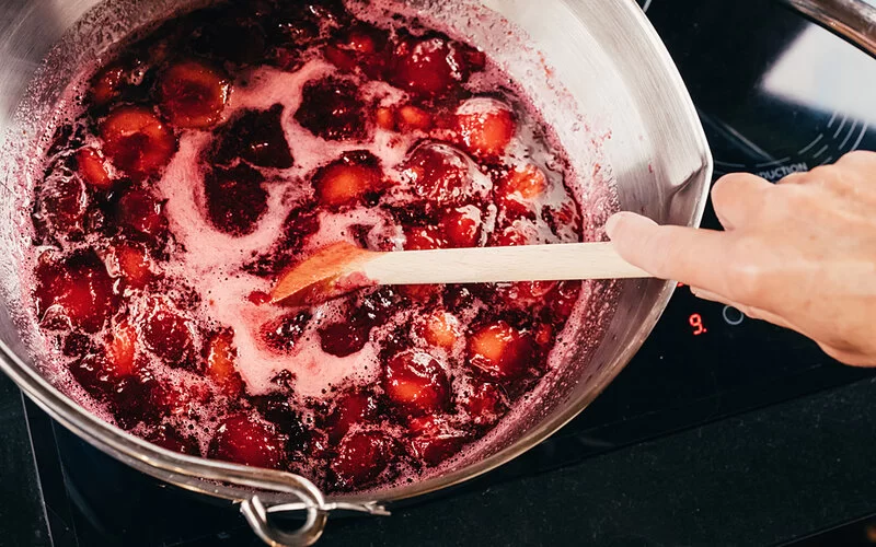 Jemand kocht eine Marmelade ohne Zucker in einem Topf auf dem Herd.