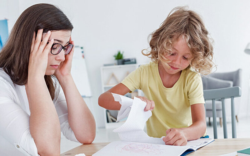 Eine Mutter ist genervt, weil ihr Kind das Schulheft zerreißt, anstatt seine Hausaufgaben zu machen.