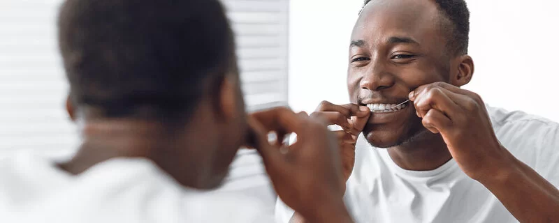 Mann benutzt Zahnseide, um Krankheiten vorzubeugen, denn Gesundheitsvorsorge ist mehr als nur Hautkrebs erkennen.