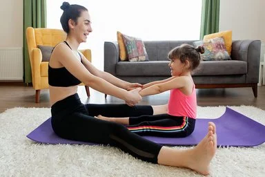 Mutter macht gemeinsam mit ihrem Kind Sport auf dem Boden im Wohnzimmer.