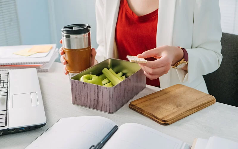 Gesunde Snacks in einer Frischhaltedose auf dem Schreibtisch.