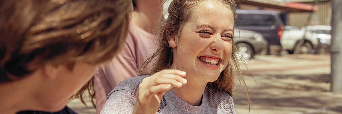 Teenagerin lacht beherzt mit ihren Freunden, weil sie weiß, Lachen ist gesund.