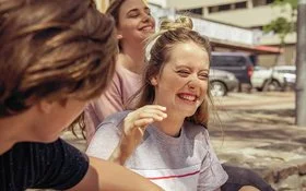 Teenagerin lacht beherzt mit ihren Freunden, weil sie weiß, Lachen ist gesund.