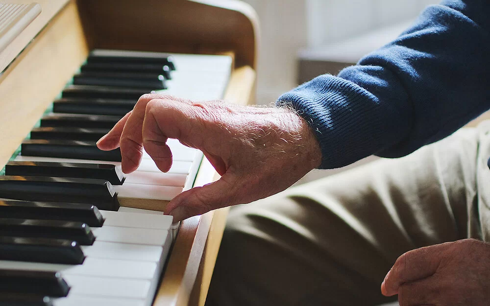 Nahaufnahme der Hand eines alten Mannes, die Klavier spielt.