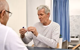 Ein Arzt erklärt einem Patienten, wie Inhalatoren zu bedienen sind. Die AOK übernimmt die Kosten für die Behandlung von Asthma und anderen chronischen Erkrankungen.