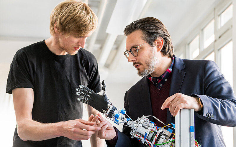 Dr.-Ing. Sami Haddadin und Kollege mit Roboterarm.