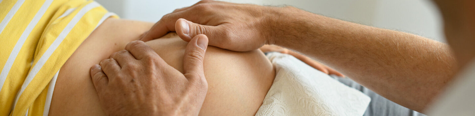 Ein Arzt tastet den Bauch einer Schwangeren ab. Bei Risikoschwangerschaften sind regelmäßige Untersuchungen besonders wichtig.
