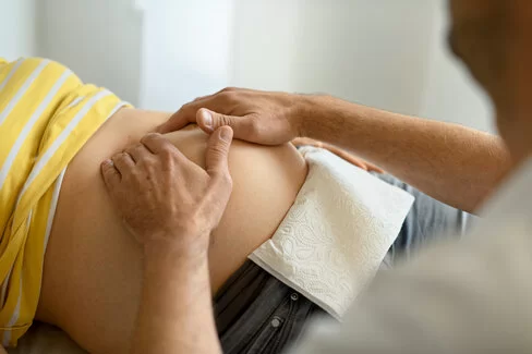 Ein Arzt tastet den Bauch einer Schwangeren ab. Bei Risikoschwangerschaften sind regelmäßige Untersuchungen besonders wichtig. 