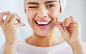 Eine Frau reinigt ihre Zähne mit Zahnseide.