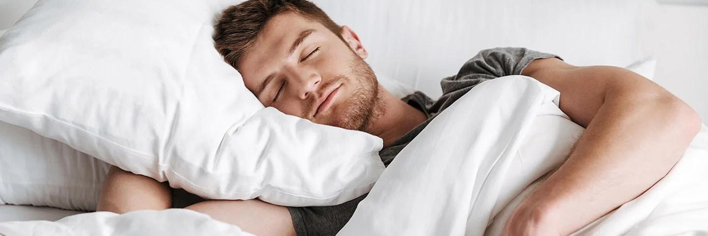 Ein Mann liegt seitlich in einem Bett und schläft.